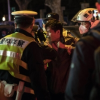 Police officers detain a man in Shanghai on Sunday night. In a country where protests are swiftly quashed, many who gathered to voice their discontent over COVID-19 lockdown, rules under the watchful eye of the police, were uncertain about how far to go.  | THE NEW YORK TIMES