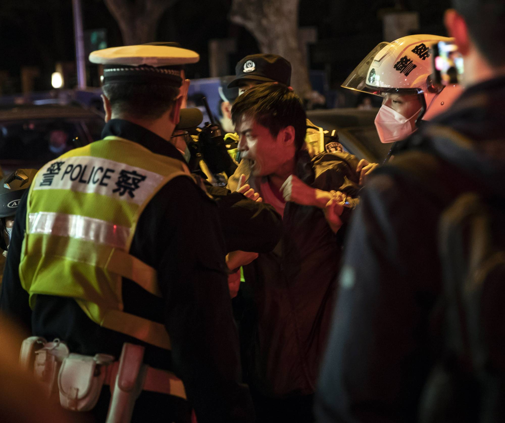 Police officers detain a man in Shanghai on Sunday night. In a country where protests are swiftly quashed, many who gathered to voice their discontent over COVID-19 lockdown, rules under the watchful eye of the police, were uncertain about how far to go. | The New York Times