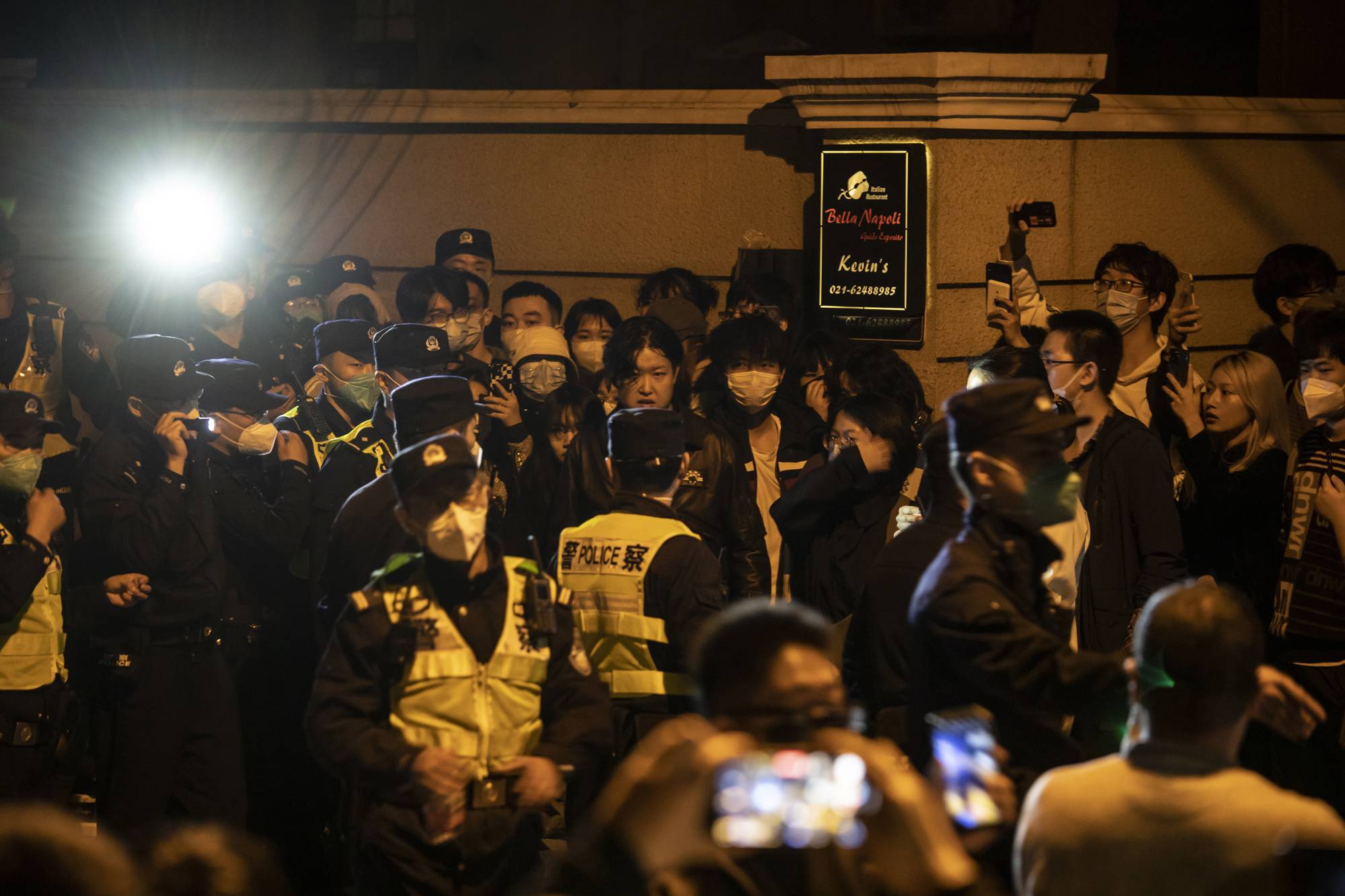 Police officers block Urumqi Road, where protests had taken place the night before, in Urumqi, China, on Sunday. Many people suspected that a COVID-19 lockdown had hampered rescue efforts or trapped victims inside their homes during a deadly fire over the weekend, and though officials denied that had happened, angry comments flooded social media and residents took to the streets in the city where the fire erupted. | The New York Times