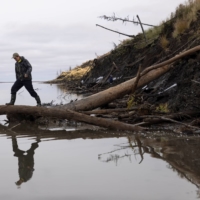A man walks along the bank of the Kolyma River at Duvanny Yar in Russia in September 2021. Duvanny Yar gives a side-on view of the permafrost thaw taking place underground where ancient Pleistocene-era flora and fauna have been trapped frozen for millennia.  | REUTERS