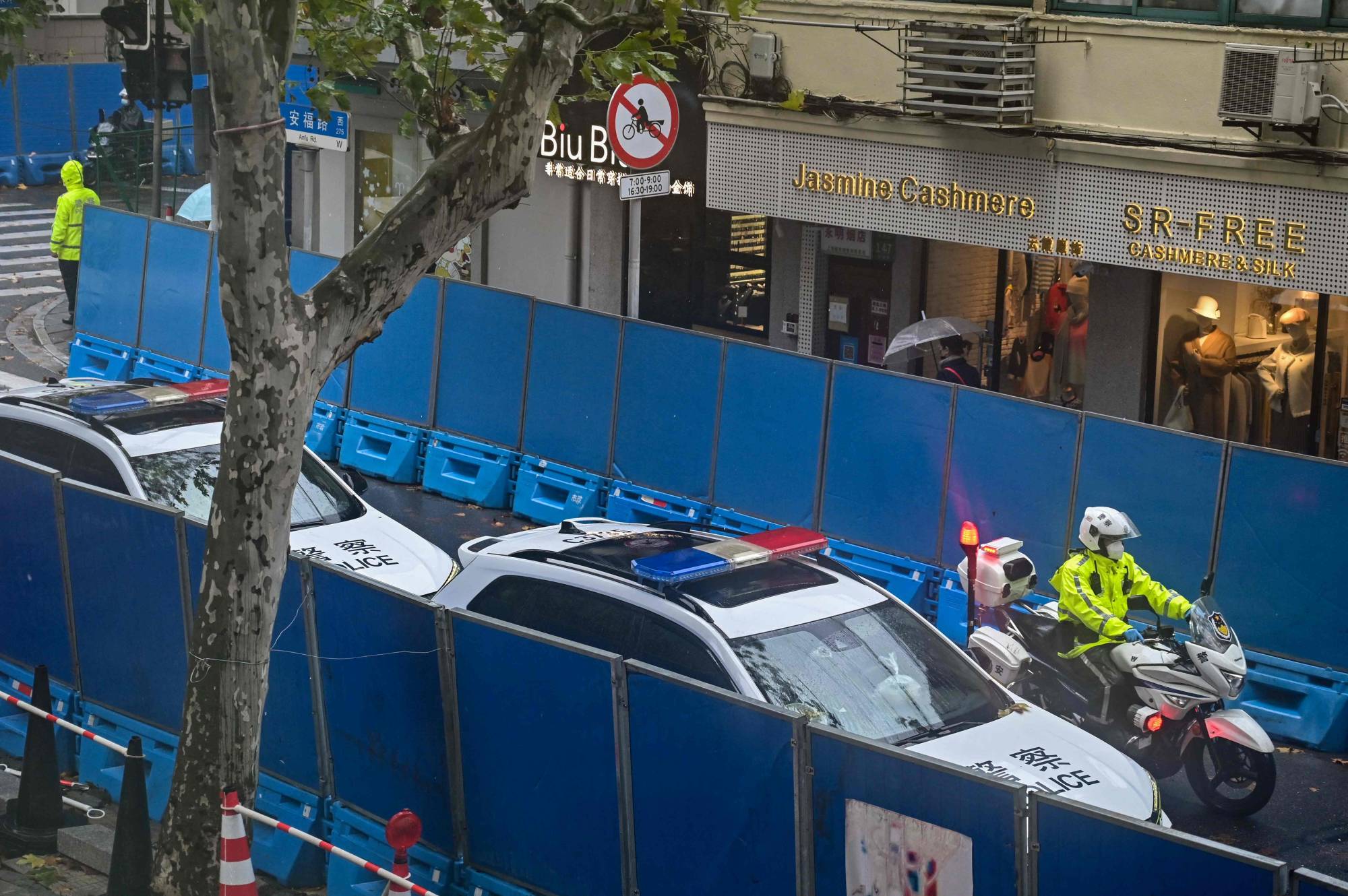 Police vehicles are seen next to Wulumuqi Road, named for Urumqi in Mandarin, in Shanghai on Tuesday, days after rare protests against China's 'COVID-zero' policy following a deadly fire in Urumqi, the capital of the Xinjiang region.  | AFP-JIJI