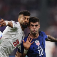 Iranian defender Ramin Rezaeian (left) fights for the ball with U.S. forward Christian Pulisic during their 2022 FIFA World Cup Group B match between Iran and the United States in Doha on Tuesday. | AFP-JIJI