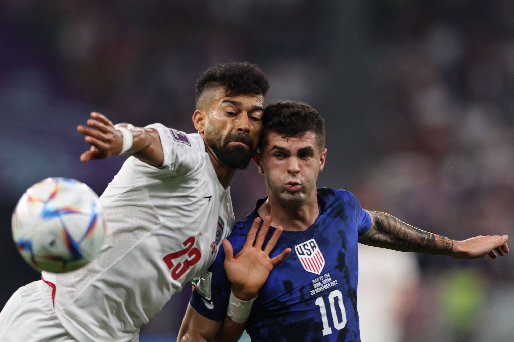 Iranian defender Ramin Rezaeian (left) fights for the ball with U.S. forward Christian Pulisic during their 2022 FIFA World Cup Group B match between Iran and the United States in Doha on Tuesday. | AFP-JIJI