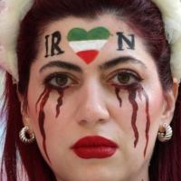 An Iran supporter with her face made up to show tears of blood under a heart in the Iranian colors, poses for photographs ahead of the 2022 FIFA World Cup match between Wales and Iran in Doha on Friday. Iran has been rocked by more than seven weeks of nationwide protests over the death of 22-year-old Kurdish Iranian woman Masha Amini while in the custody of the Tehran morality police  | AFP-JIJI