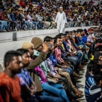 Migrant workers watch the World Cup match between Brazil and Switzerland on a big screen at a large cricket stadium on the outskirts of Doha on Monday. | AFP-JIJI