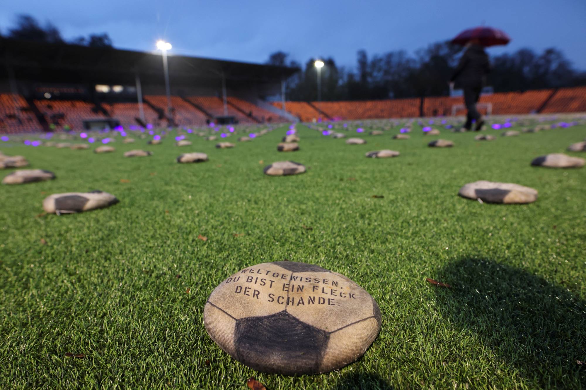 Flat soccer balls filled with sand set by the artist Volker-Johannes Trieb are seen during the opening game of the 2022 FIFA World Cup to commemorate what activists say are deaths of thousands of workers who lost their lives to build the stadiums for the tournament in Qatar, in Herne, Germany, on Nov. 20. | REUTERS