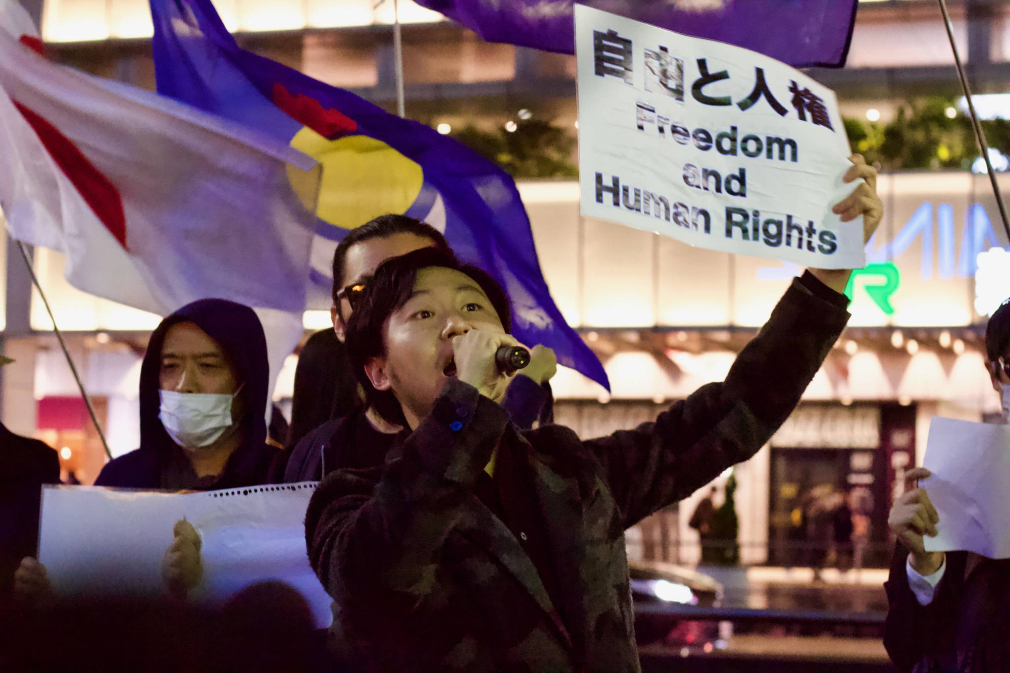 A speaker calls for greater human rights protections in China during a demonstration outside JR Shinjuku Station in Tokyo on Wednesday. | ELIZABETH BEATTIE