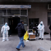 Pandemic prevention workers in protective suits get ready to enter an apartment building that went into lockdown as COVID-19 outbreaks continue in Beijing, on Friday. | REUTERS