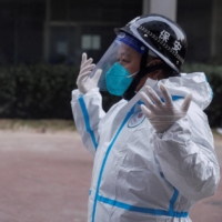 Pandemic prevention workers in protective suits get ready to enter an apartment building that went into lockdown as coronavirus  outbreaks continue in Beijing on Friday. | REUTERS