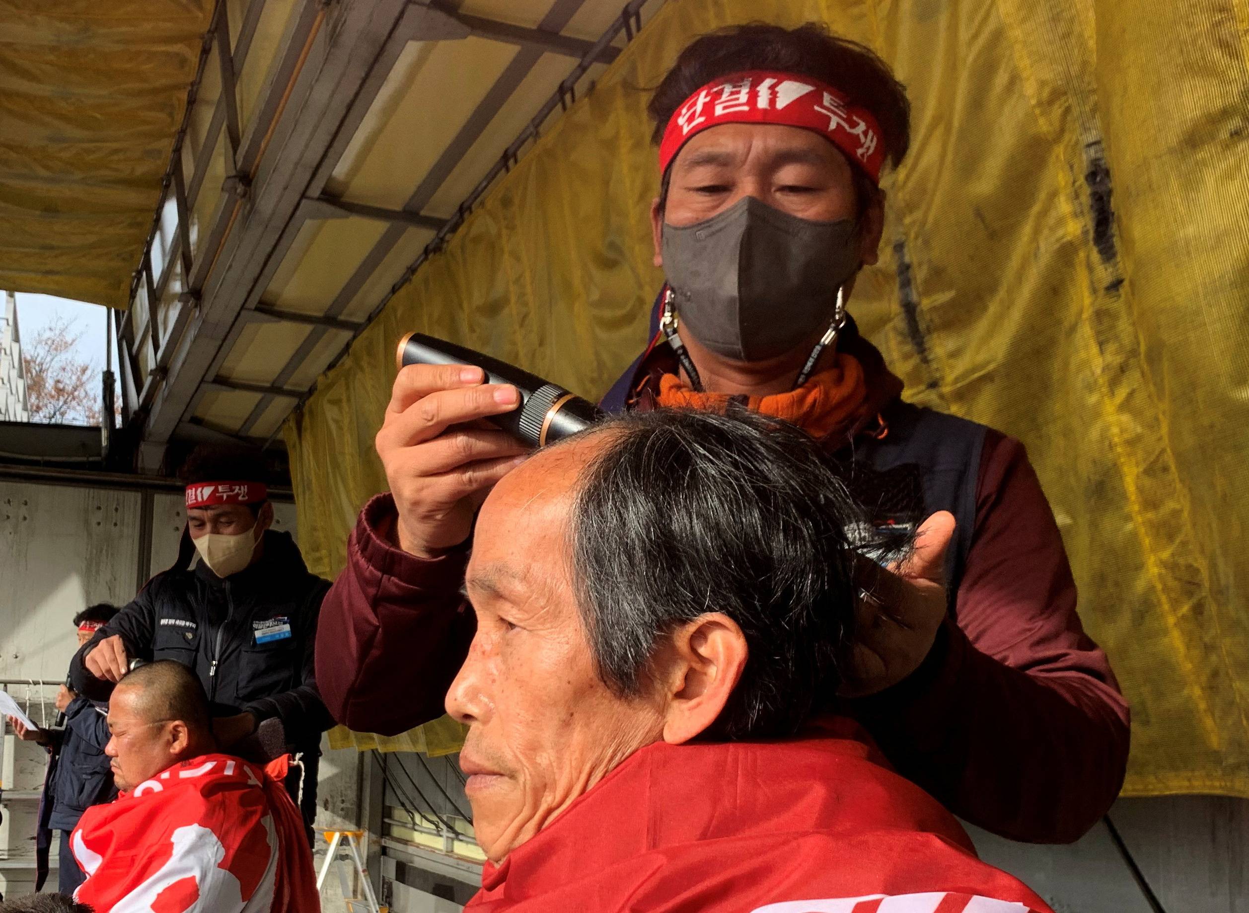 Unionized truck drivers have their hair shaved at a protest to oppose President Yoon Suk-yeol issuing a back-to-work order for truckers demonstrating in Uiwang, South Korea, on Tuesday. | REUTERS