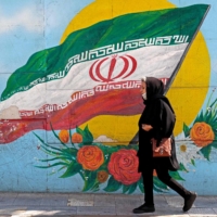 A woman walks past a mural in the Iranian capital Tehran in October. | AFP-JIJI