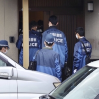 Police investigators enter the head office of a group that claims to be the Japanese arm of U.S. conspiracy cult QAnon, in Fukuroi, Shizuoka Prefecture, on Monday. | KYODO