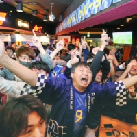 Soccer fans celebrate in Tokyo\'s Shibuya area on Friday after Japan advanced to the round of 16 by beating Spain. | KYODO

