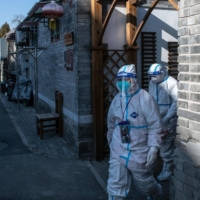 Workers in protective gear in Beijing on Tuesday. | BLOOMBERG