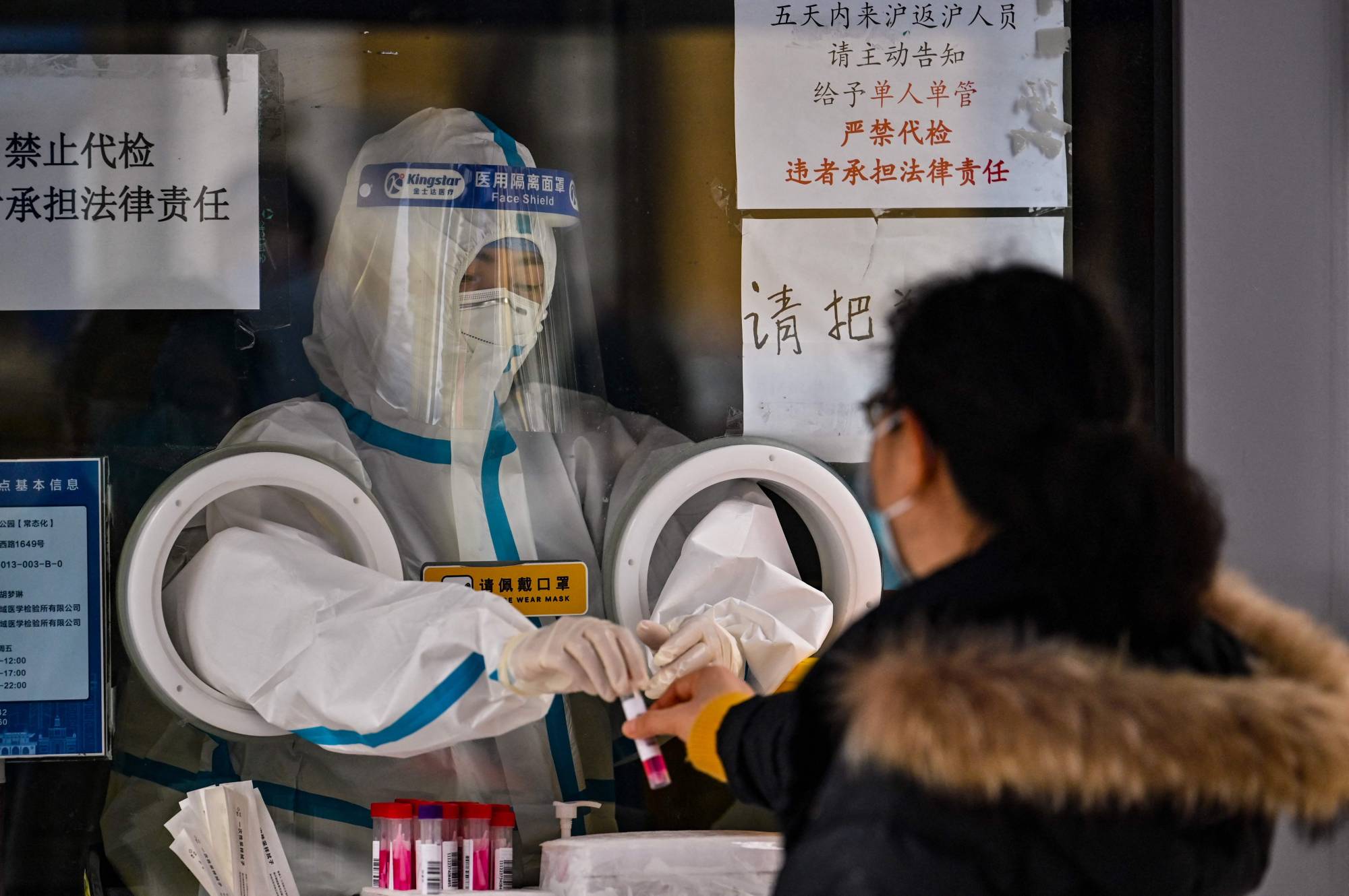 A health worker prepares to take a swab sample from a woman to test for COVID-19 in the Jing'an district in Shanghai on Thursday. | AFP-Jiji