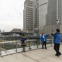 Sightseers at a walkway in the Lujiazui Financial District in Shanghai on Thursday.  | QILAI SHEN / THE NEW YORK TIMES