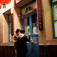 A waiter guides a customer to scan a health QR code outside a restaurant in Shanghai on Thursday.  | REUTERS