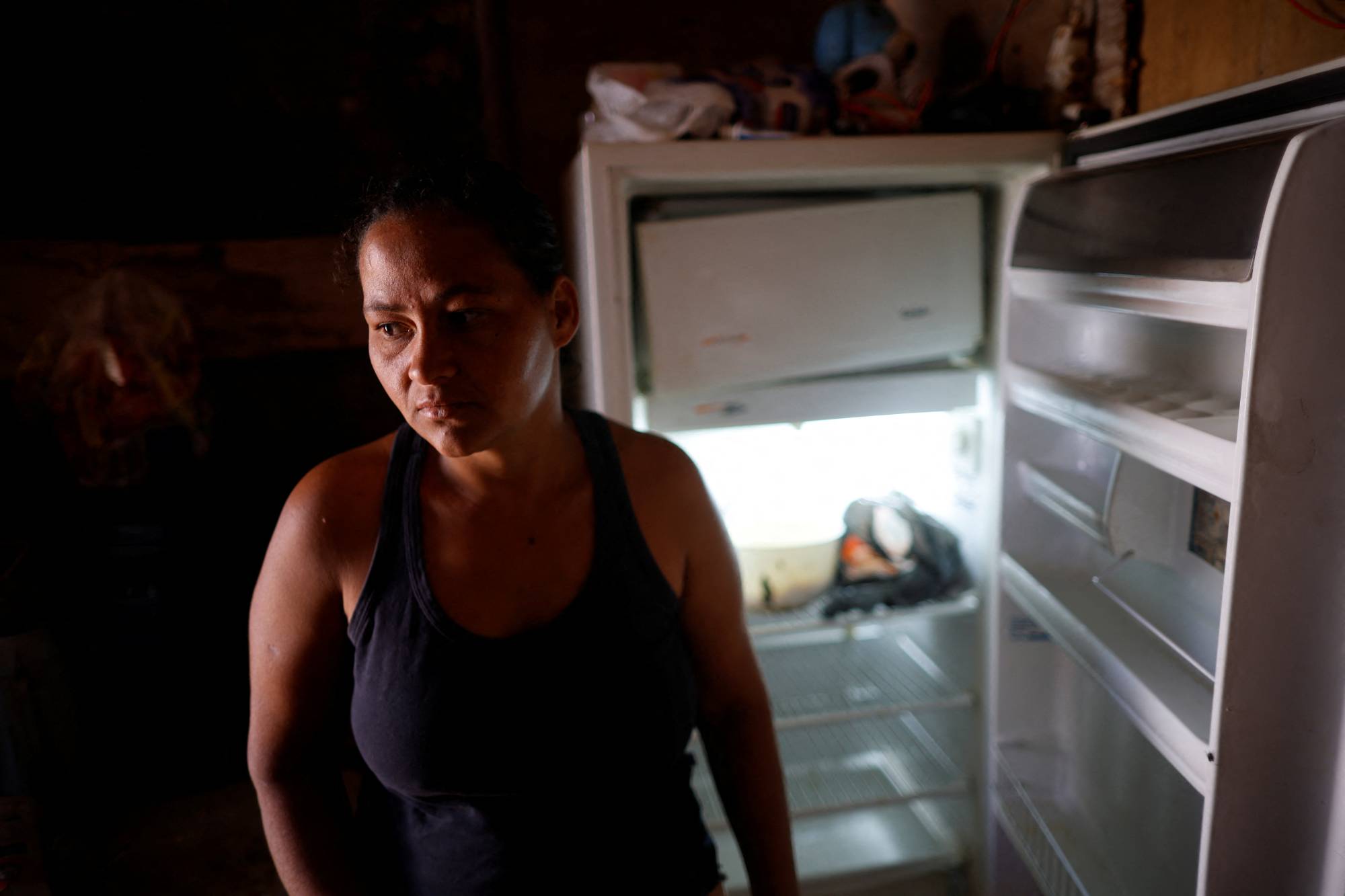 A woman stands in front of her empty fridge at her home in Brasilia in September. Rapid inflation across the world has pushed some households to the brink. | REUTERS