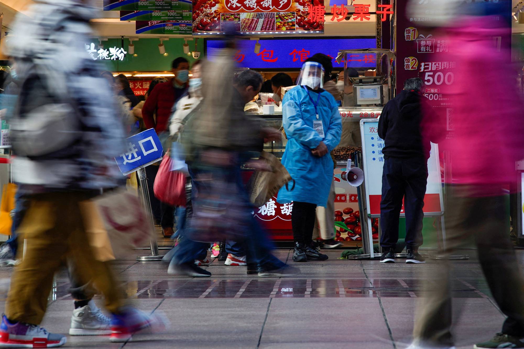 A worker in a protective suit at a food shop in Shanghai on Monday. The world’s second-biggest economy is rapidly dismantling restrictions that largely kept COVID-19 at bay for almost three years.  | REUTERS 
