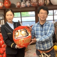 A JR East employee poses with a craftsman at a <i>daruma</i> (lucky doll) workshop during an online tour for Singapore in September. | EAST JAPAN RAILWAY COMPANY
