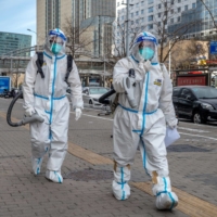 Workers wearing protective gear in Beijing on Thursday. Bucking expectations for a managed and gradual transition, Chinese President Xi Jinping\'s government is now allowing the virus to run rampant. | BLOOMBERG