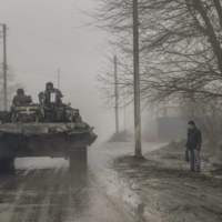 A civilian watches as Ukrainian troops pass by on Friday in the Bakhmut district of eastern Ukraine, where the city and outlying areas continue to come under Russian attack. | TYLER HICKS / THE NEW YORK TIMES