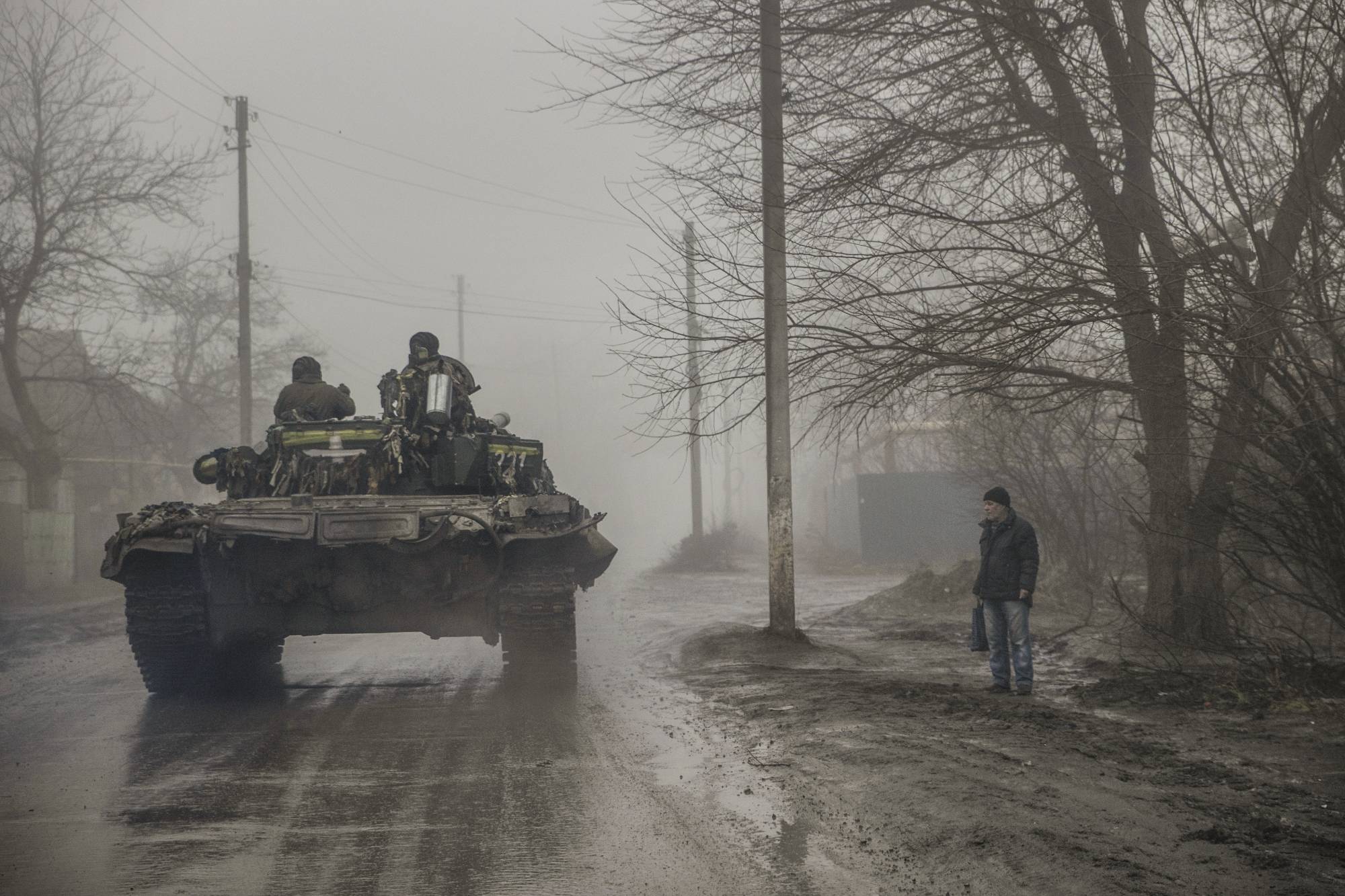 A civilian watches as Ukrainian troops pass by on Friday in the Bakhmut district of eastern Ukraine, where the city and outlying areas continue to come under Russian attack. | Tyler Hicks / The New York Times