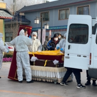 Workers transfer a body in a casket at a funeral home in Beijing on Saturday. | REUTERS