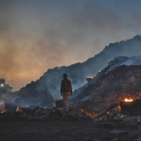 A man stands near burning coal waste inside a coal mine in Sonbhadra, India, in November 2021. | RITESH SHUKLA / GETTY IMAGES