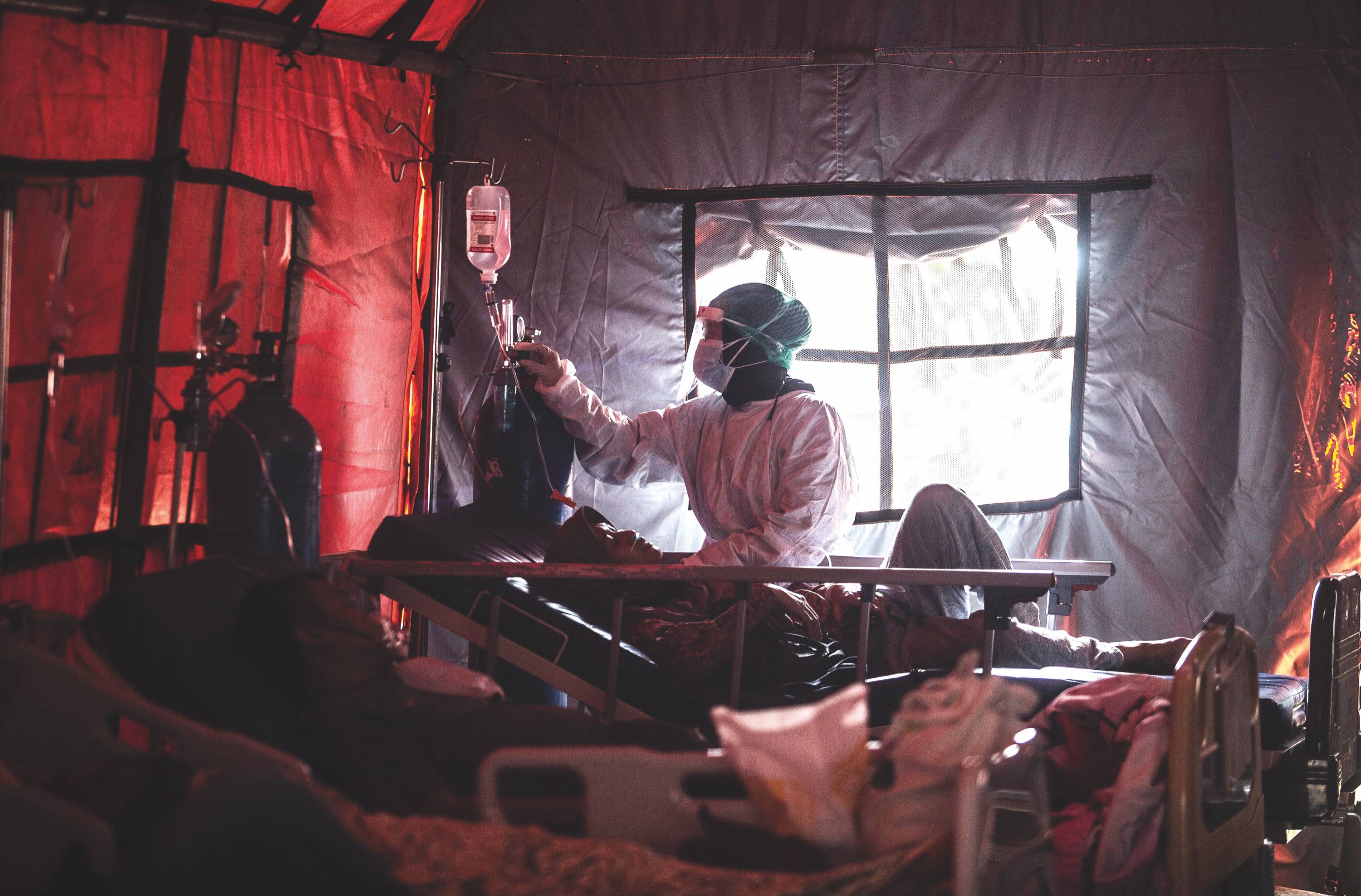 Medical personnel tend to COVID-19 patients in a tent set up outside a hospital in Bogor, Indonesia, in June 2021. | ADITYA AJI / AFP / VIA GETTY IMAGES