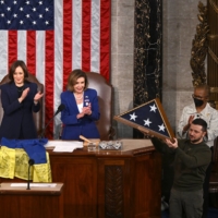 Ukrainian President Volodymyr Zelenskyy holds an American flag that was gifted to him by U.S. House Speaker Nancy Pelosi (center) after he addressed a joint meeting of Congress on Capitol Hill in Washington on Wednesday. | KENNY HOLSTON / THE NEW YORK TIMES