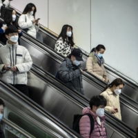 Commuters in Shanghai on Tuesday. China appears to be seeing an increase in COVID-19 deaths across a swath of the country that aren\'t being reported in government figures. | BLOOMBERG