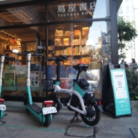 Luup e-scooters and an e-bike at a pickup point in Tokyo\'s Meguro Ward on Dec. 19. New e-scooter regulations introduced earlier this year mean that by April 2024, a driver\'s license will no longer be required — helmets, meanwhile, are currently advised but at the discretion of the user. | CHRIS RUSSELL