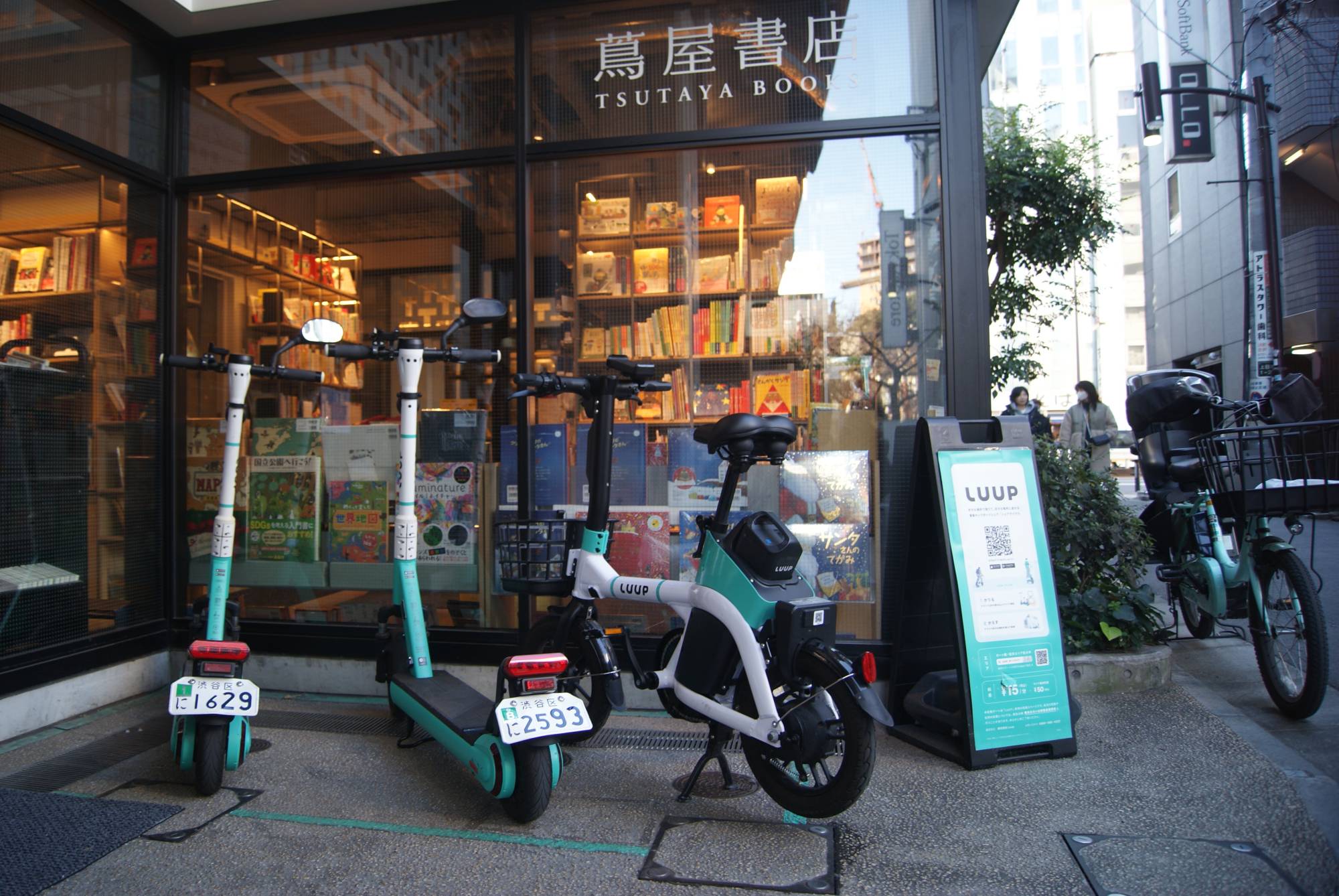 Luup e-scooters and an e-bike at a pickup point in Tokyo's Meguro Ward on Dec. 19. New e-scooter regulations introduced earlier this year mean that by April 2024, a driver's license will no longer be required — helmets, meanwhile, are currently advised but at the discretion of the user. | CHRIS RUSSELL