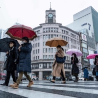 People cross the street in Tokyo\'s Ginza district on Thursday. Average winter bonuses at major companies showed the sharpest increase since the current calculation method was adopted in 1981, as Japan recovers from the COVID-19 pandemic. | AFP-JIJI