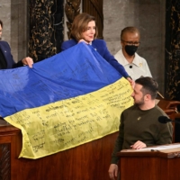 President Volodymyr Zelenskyy gives a Ukrainian national flag to U.S. House Speaker Nancy Pelosi and Vice President Kamala Harris during his address to a joint session of Congress in Washington on Wednesday. | AFP-JIJI