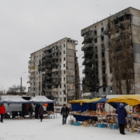 Residents buy food at a street market in front of buildings damaged by Russian strikes, in Borodianka, Ukraine, on Dec. 15.
 | REUTERS 