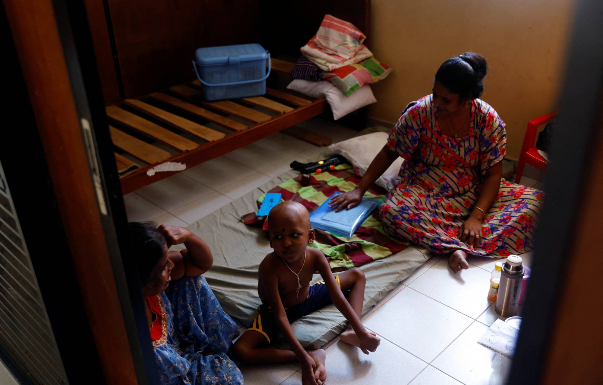 S. Saksan, 5, who has been diagnosed with leukemia, sits with his two grandmothers K. Wimalesvari, 63, and Ratnasingham Rajini, 45, at a cancer center near a hospital in Colombo. | Reuters
