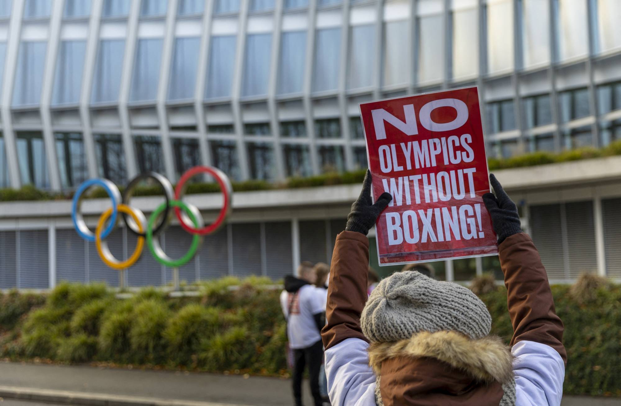 Protesters hold up signs in support of boxing's inclusion at the Olympics outside the International Olympic Committee's headquarters in Lausanne, Switzerland, on Dec. 5. | REUTERS