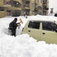 A resident removes snow in a parking lot in the city of Kitami, Hokkaido, on Saturday. | KYODO