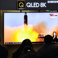 People watch a news broadcast showing file footage of a North Korean missile test at a railway station in Seoul on Friday after North Korea fired two short-range ballistic missiles, according to South Korea\'s military. | AFP-JIJI