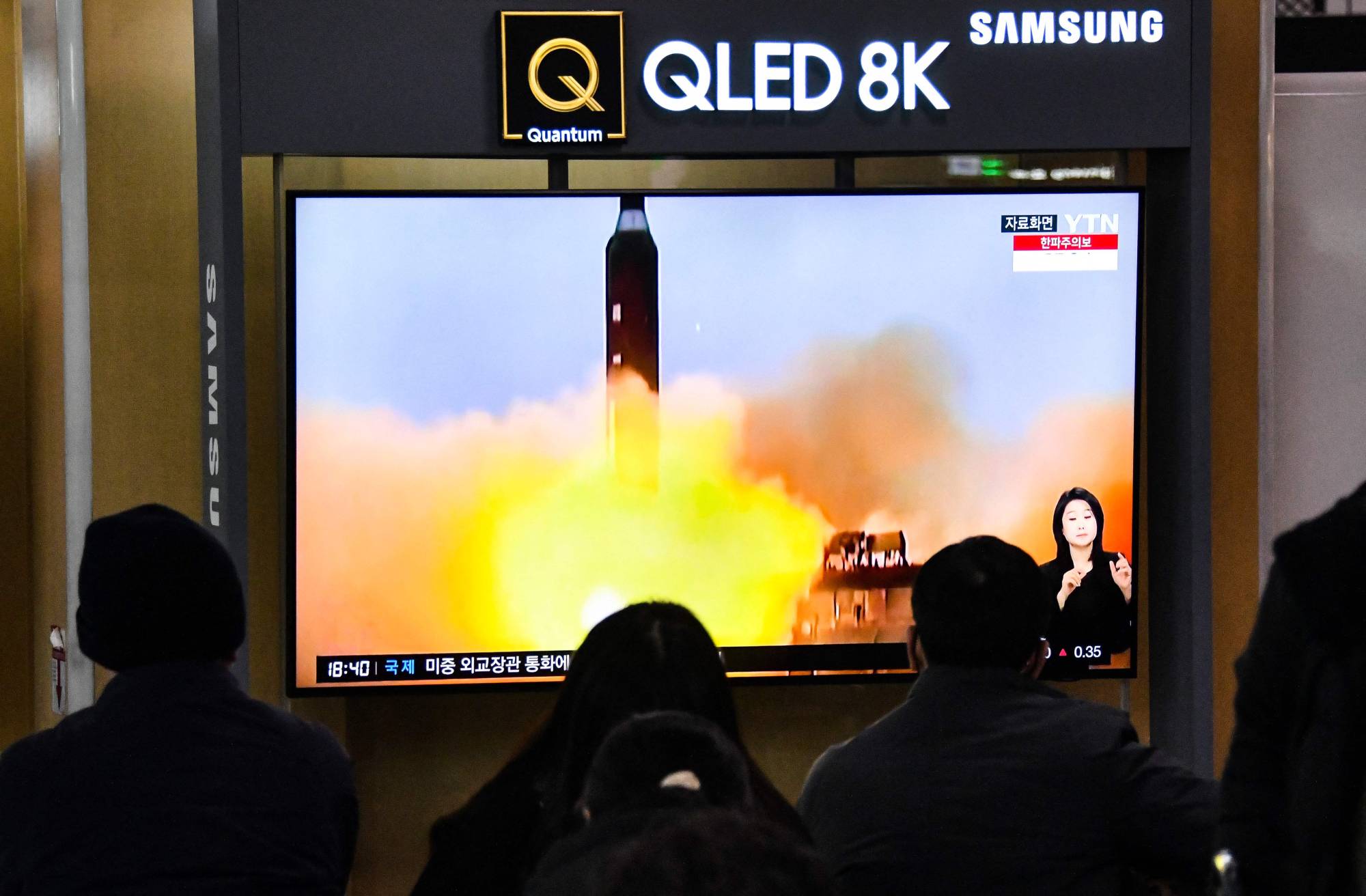 People watch a news broadcast showing file footage of a North Korean missile test at a railway station in Seoul on Friday after North Korea fired two short-range ballistic missiles, according to South Korea's military. | AFP-JIJI
