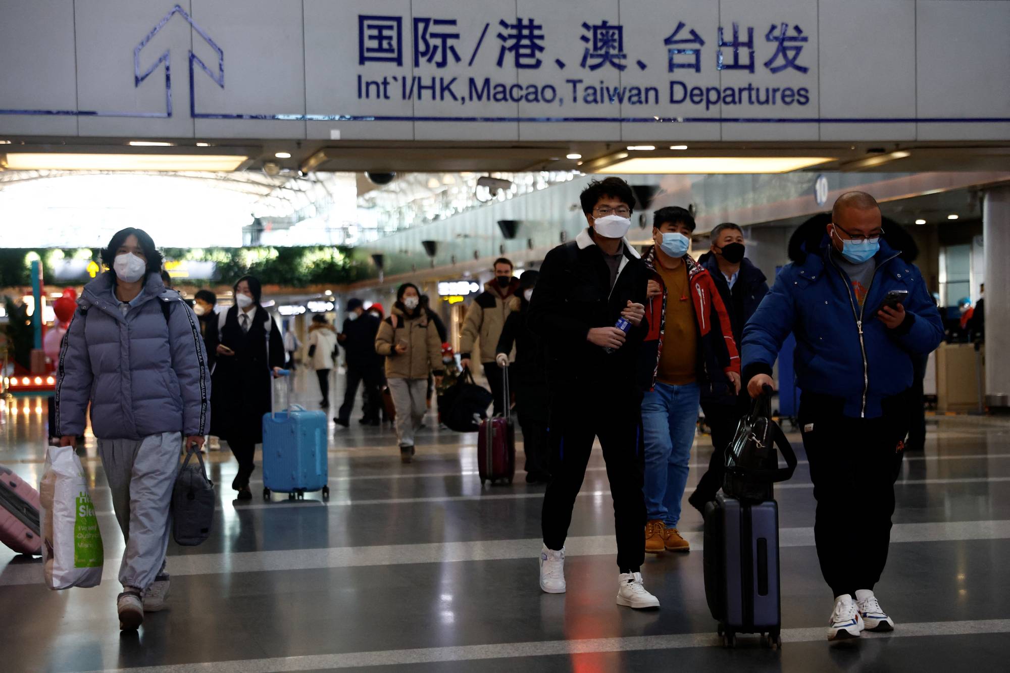 Travelers at Beijing Capital International Airport in Beijing on Tuesday | REUTERS