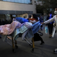 Medical workers transport an elderly patient outside a hospital in Chengdu, China, on Tuesday. | REUTERS 