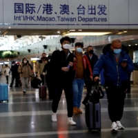 Travelers walk with their luggage at Beijing Capital International Airport on Tuesday, amid the COVID-19 outbreak in Beijing. | REUTERS