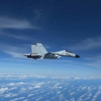 A Chinese Navy J-11 fighter jet is recorded flying close to a U.S. Air Force RC-135 aircraft in international airspace over the South China Sea, according to the U.S. military, in a still image from video taken Dec. 21.   | U.S. INDO-PACIFIC COMMAND / VIA REUTERS