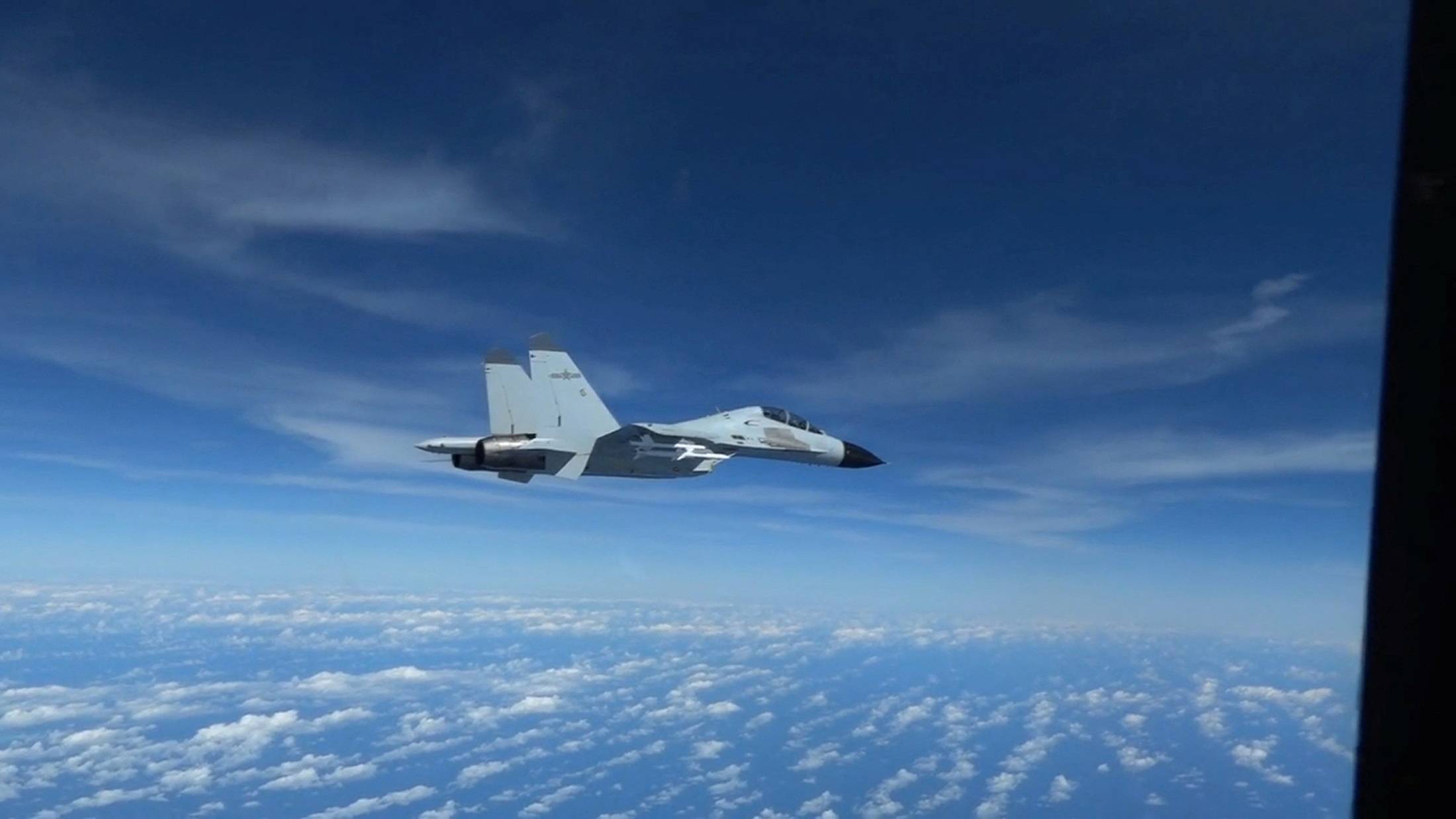 A Chinese Navy J-11 fighter jet is recorded flying close to a U.S. Air Force RC-135 aircraft in international airspace over the South China Sea, according to the U.S. military, in a still image from video taken Dec. 21.   | U.S. INDO-PACIFIC COMMAND / VIA REUTERS