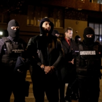 Andrew Tate and Tristan Tate are escorted by police officers outside the headquarters of the Directorate for Investigating Organized Crime and Terrorism in Bucharest on Thursday after being detained for 24 hours, in Bucharest. | REUTERS