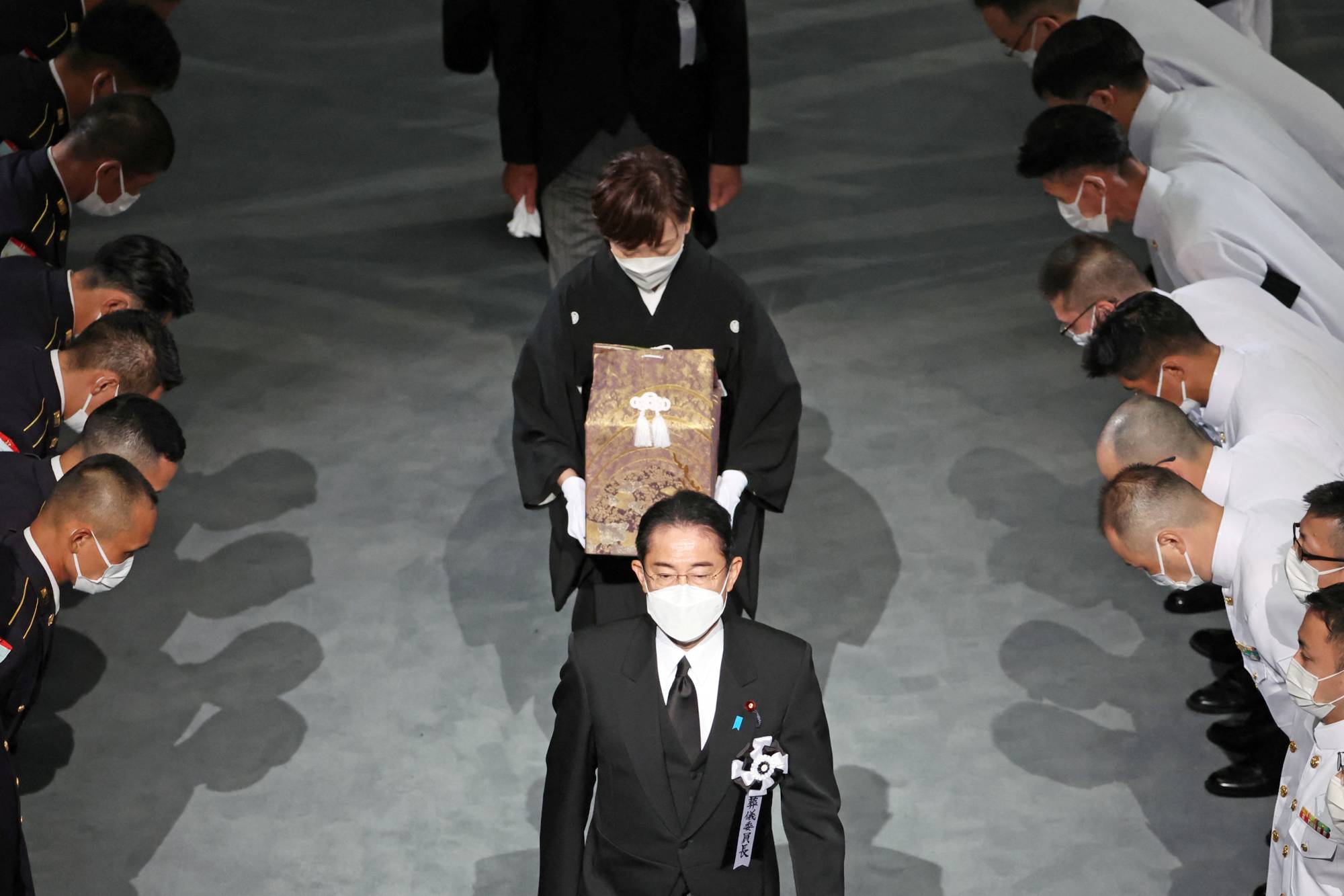 The widow of former Japanese Prime Minister Shinzo Abe, Akie, escorted by Prime Minister Fumio Kishida, carries her husband’s ashes during his state funeral in Tokyo in September after his assassination earlier in the summer.    | POOL / VIA REUTERS