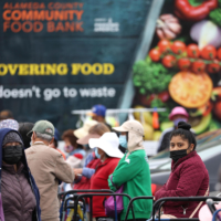 People wait for the Alameda County Community Food Bank’s giveaway in Oakland, California, in July as record inflation sent food prices soaring. | GETTY IMAGES VIA KYODO